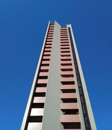 Narrow residential tower rising into a deep blue sky