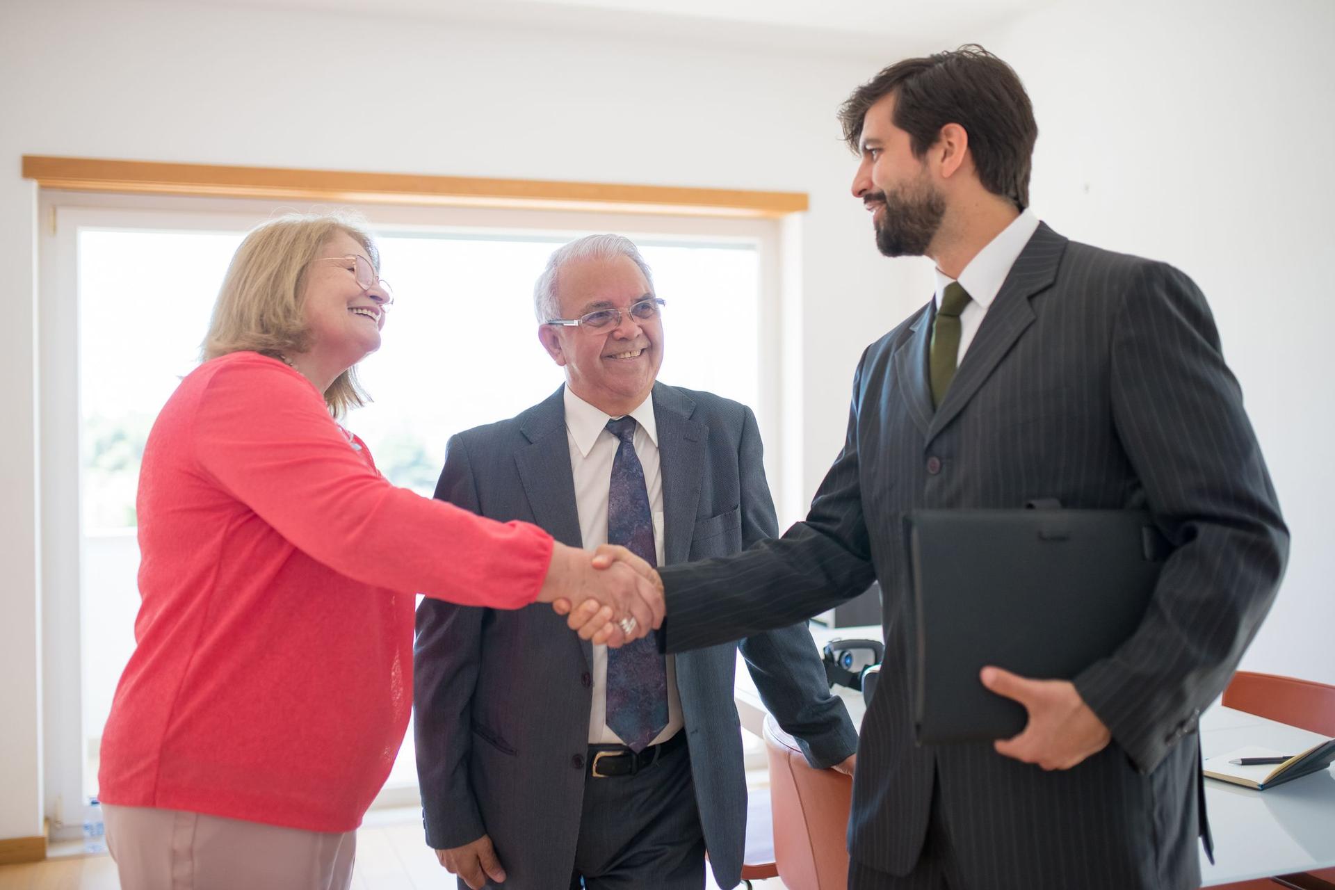 An adviser shakes hands with a buyer after agreeing terms